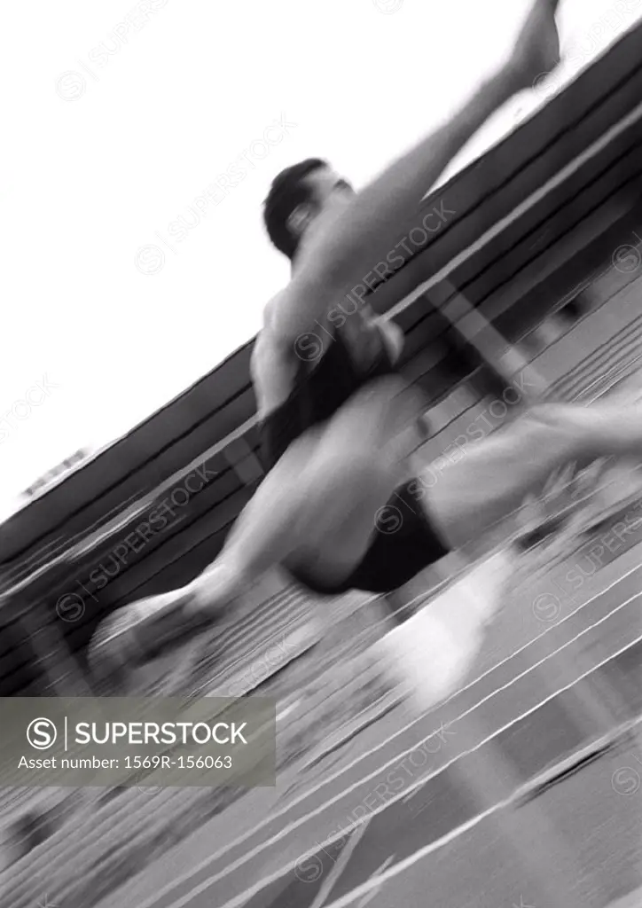 Athlete jumping hurdle, blurred motion, close-up, b&w