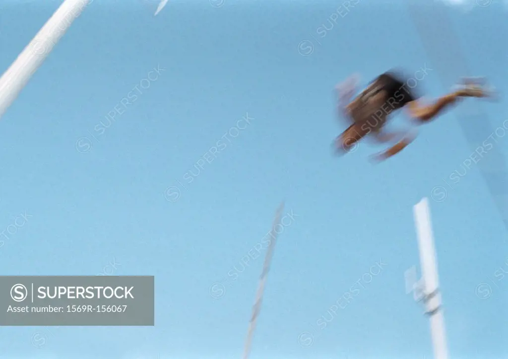 Male pole vaulter in mid-air, blurred motion