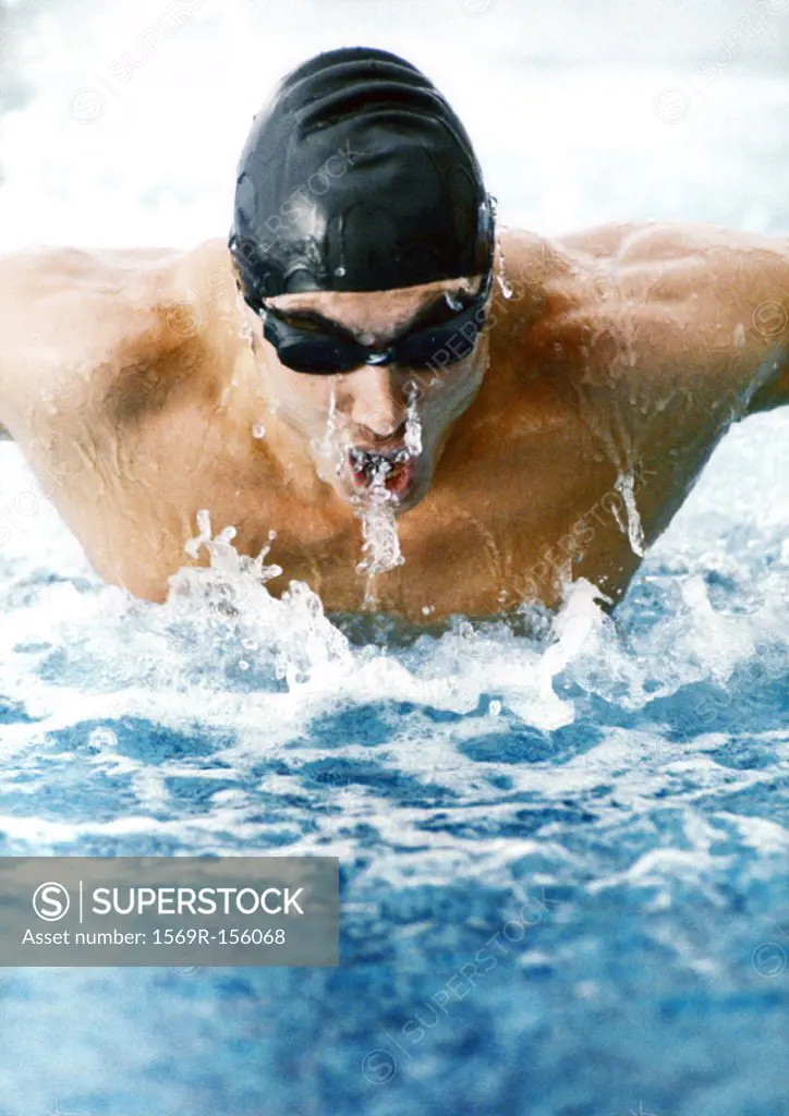 Male athlete swimming butterfly stroke, close-up