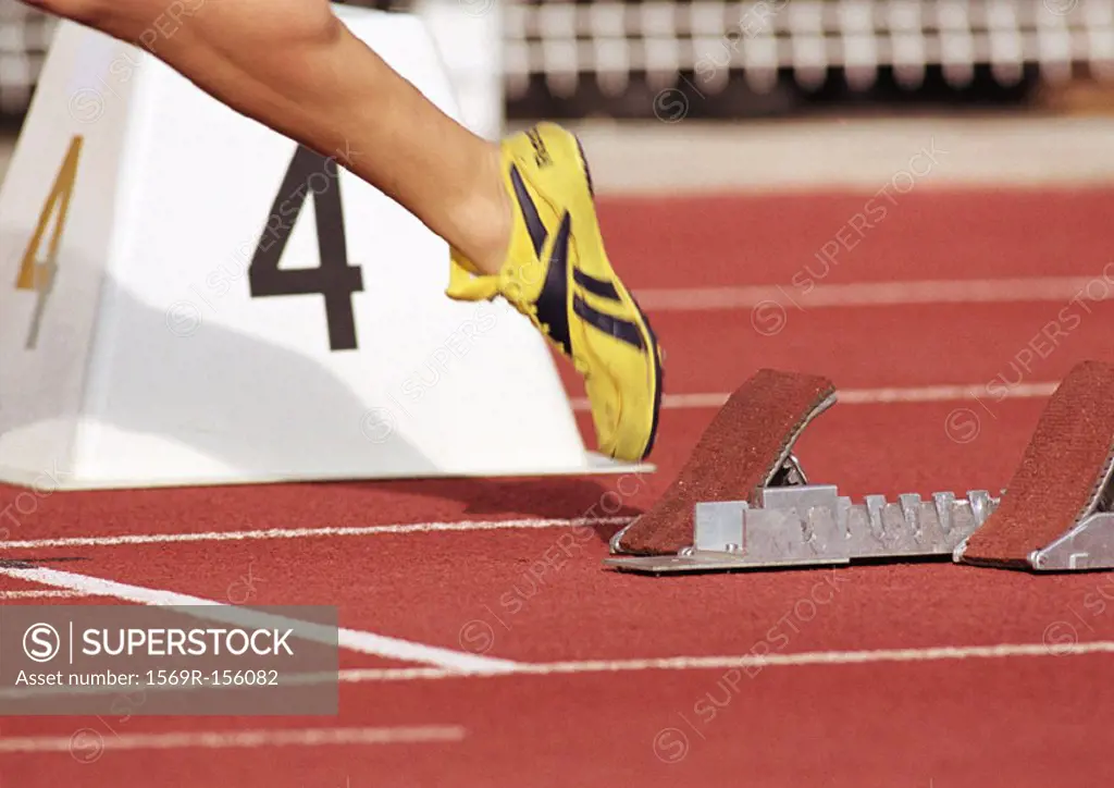 Runner leaving starting block, low section, close-up