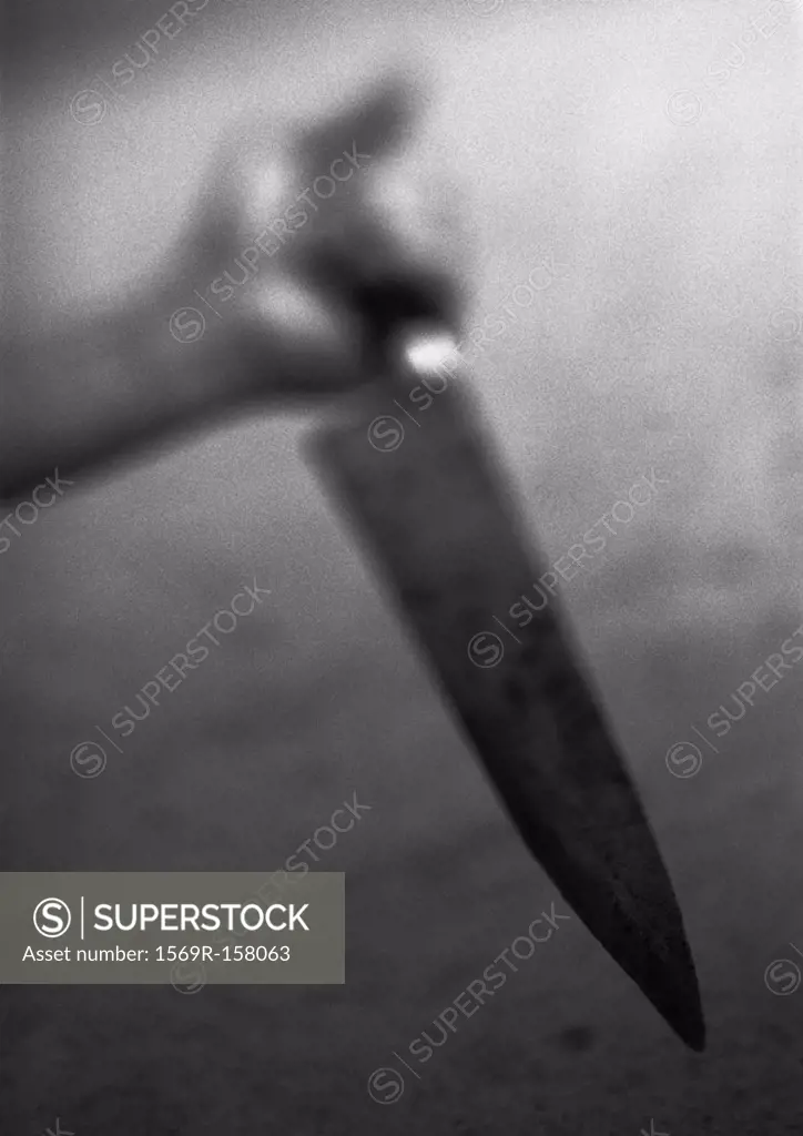 Hand holding kitchen knife, blurred, b&w