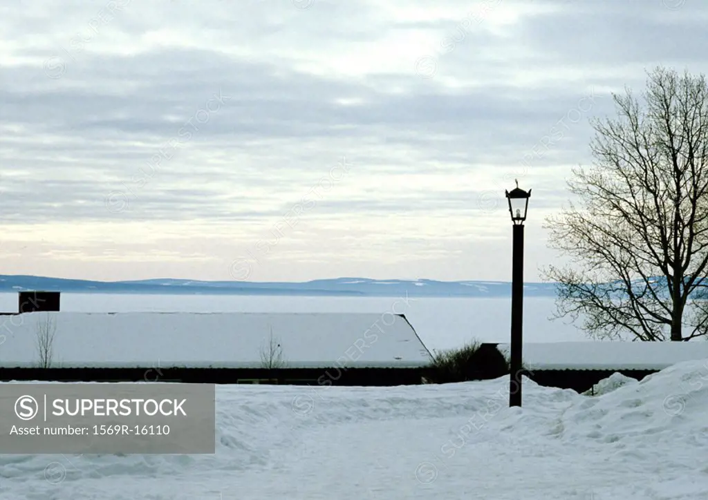 Finland, snow-covered houses near water´s edge