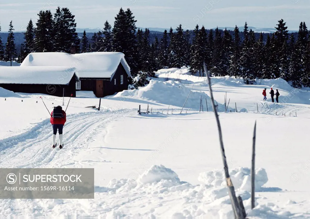 Sweden, cross country skier approaching snow-covered cabins