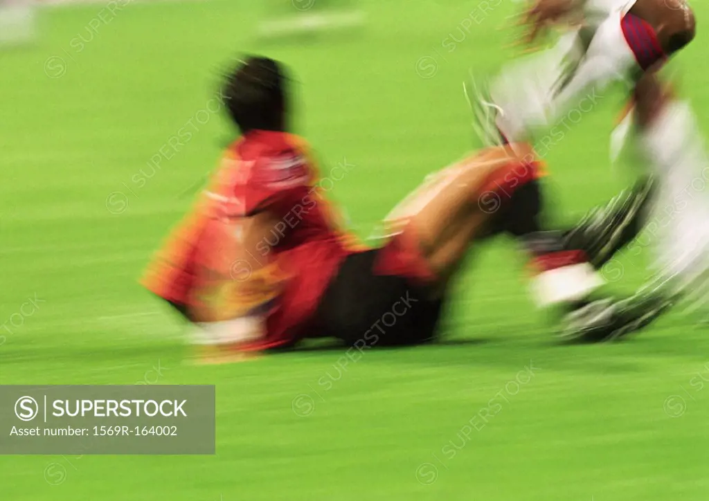 Two soccer players in match, one on field, blurred