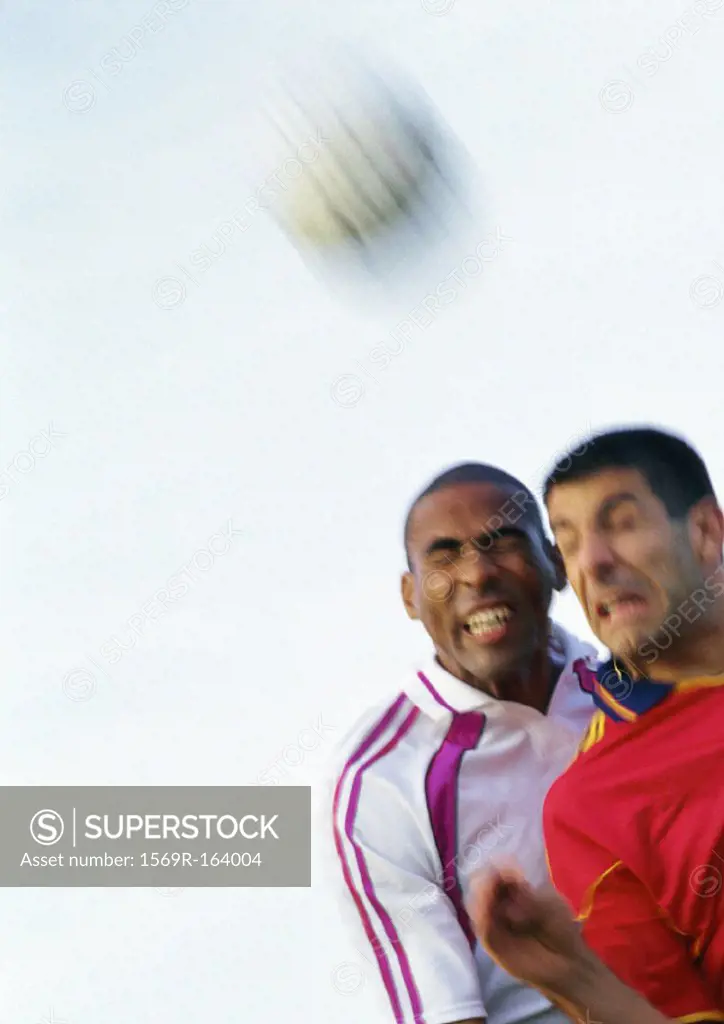 Two players competing for the ball at soccer match, portrait