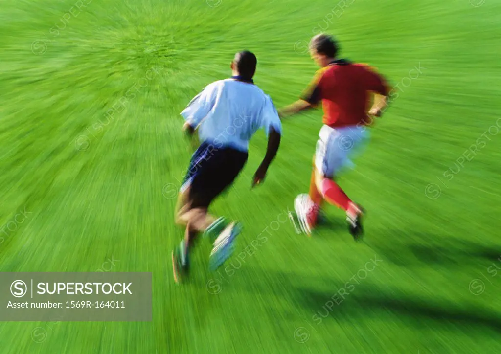 Two soccer players running for ball, blurred