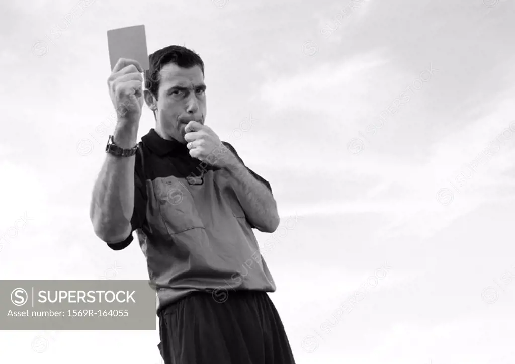 Referee in soccer match holding up card, b&w