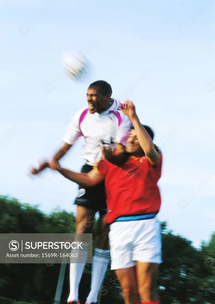 Two players jumping for ball at soccer match, blurred motion