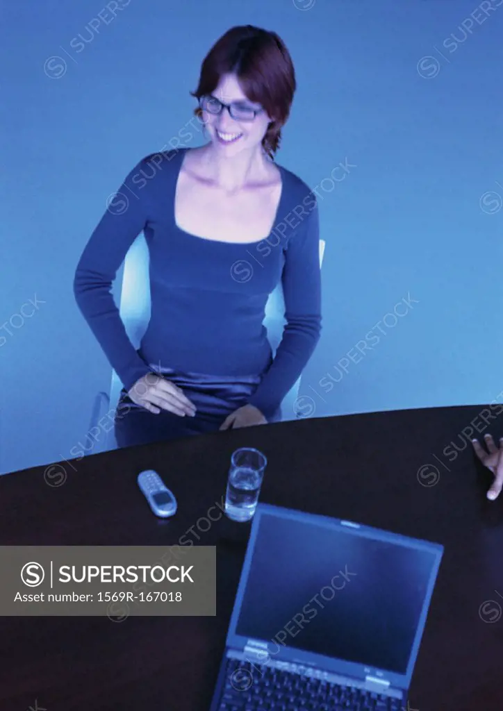 Businesswoman at desk, smiling, high angle view