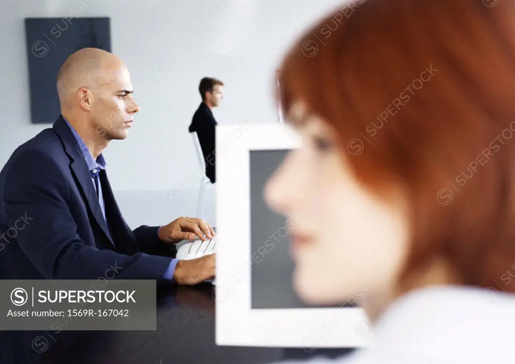 People working in office, businessman using computer, side view