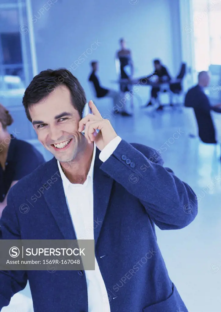 People in office, businessman using cell phone, smiling, portrait