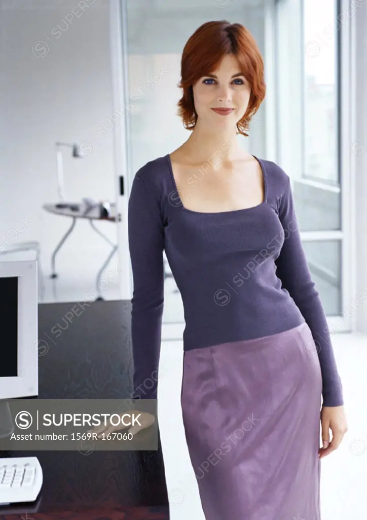 Businesswoman standing with hand on desk