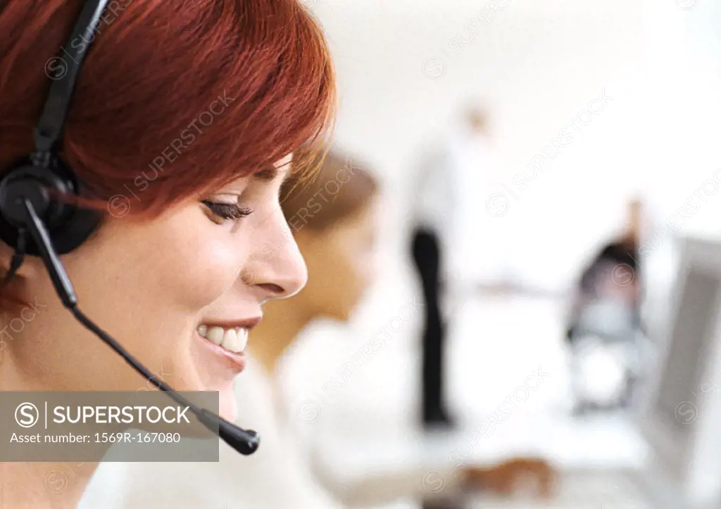 Woman wearing headset in office, side view, close-up