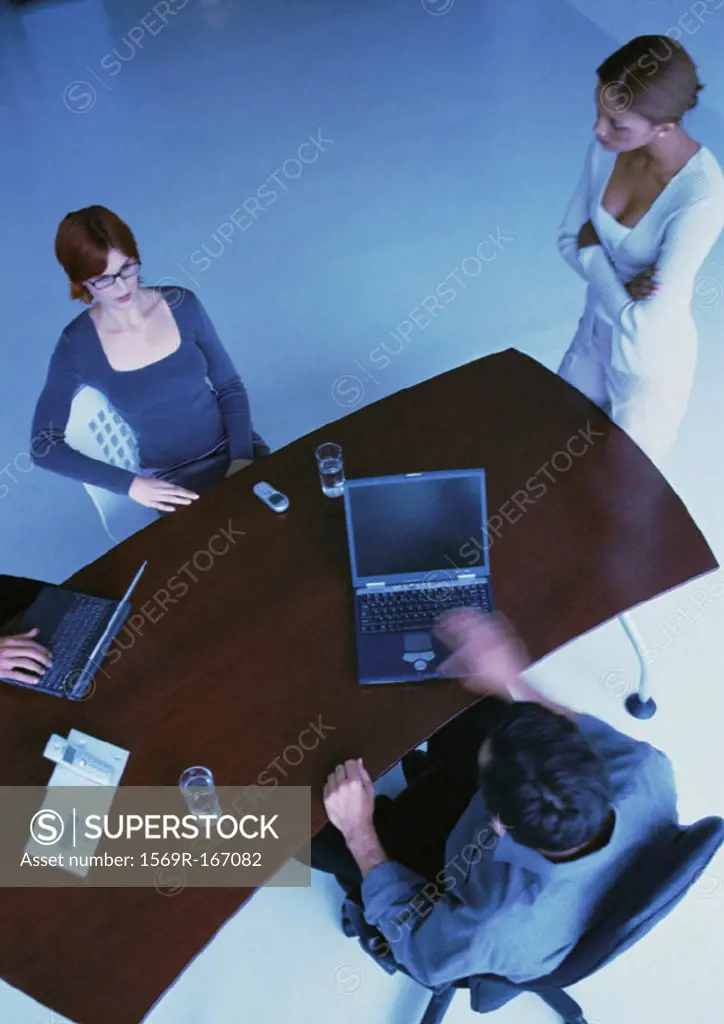 Business people around desk, two with laptops, elevated view