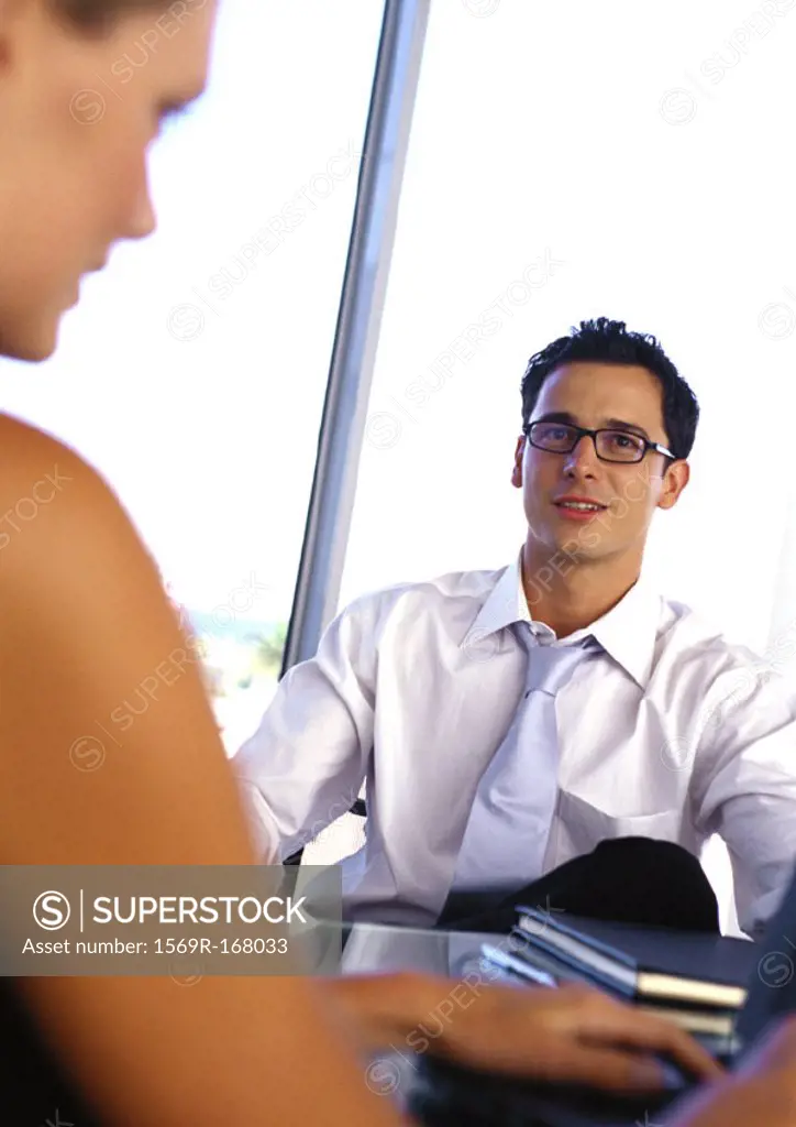 Businessman and woman, sitting at desk, portrait