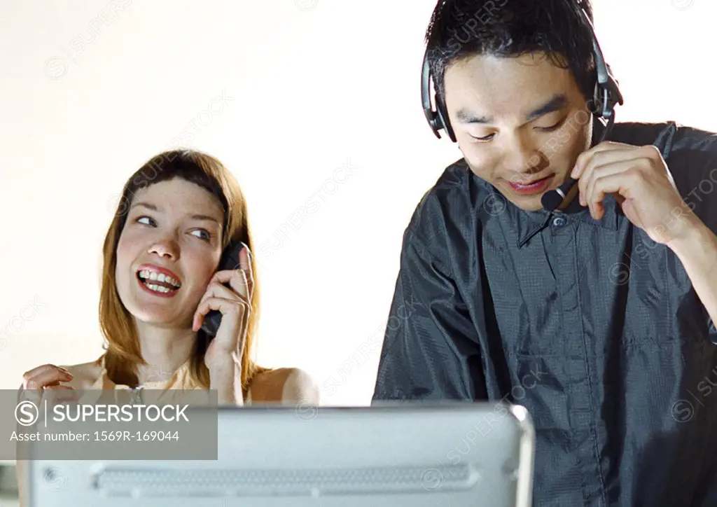 Man wearing headset, woman using cell phone
