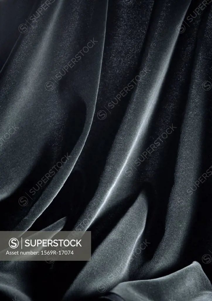 Folds in shiny black fabric, close-up, full frame