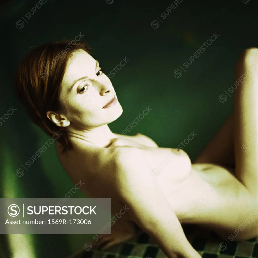 Nude woman sitting, leaning back on arms