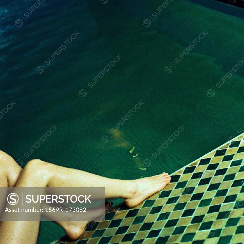 Nude legs on edge of swimming pool