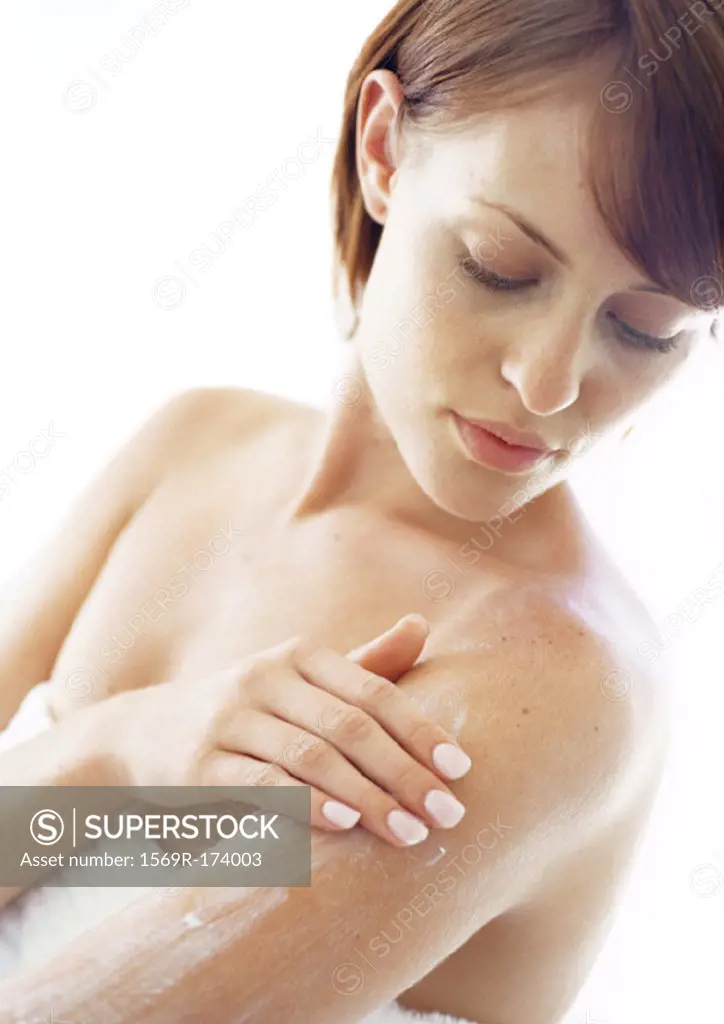 Young woman applying moisturizer to arm, close-up