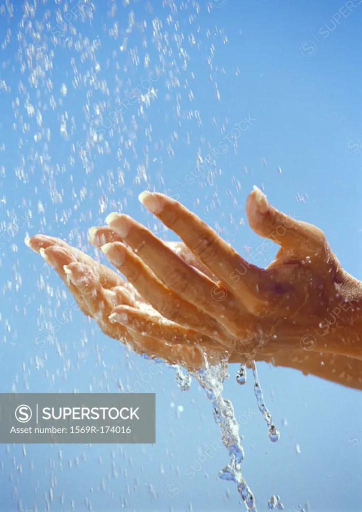 Hands under drops of water, close up
