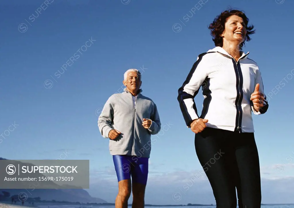 Mature couple running outdoors, low angle view