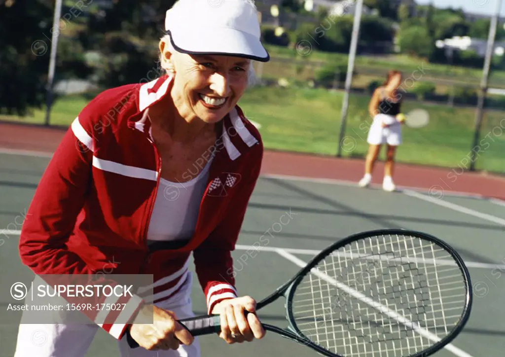 Mature woman holding tennis racket, smiling