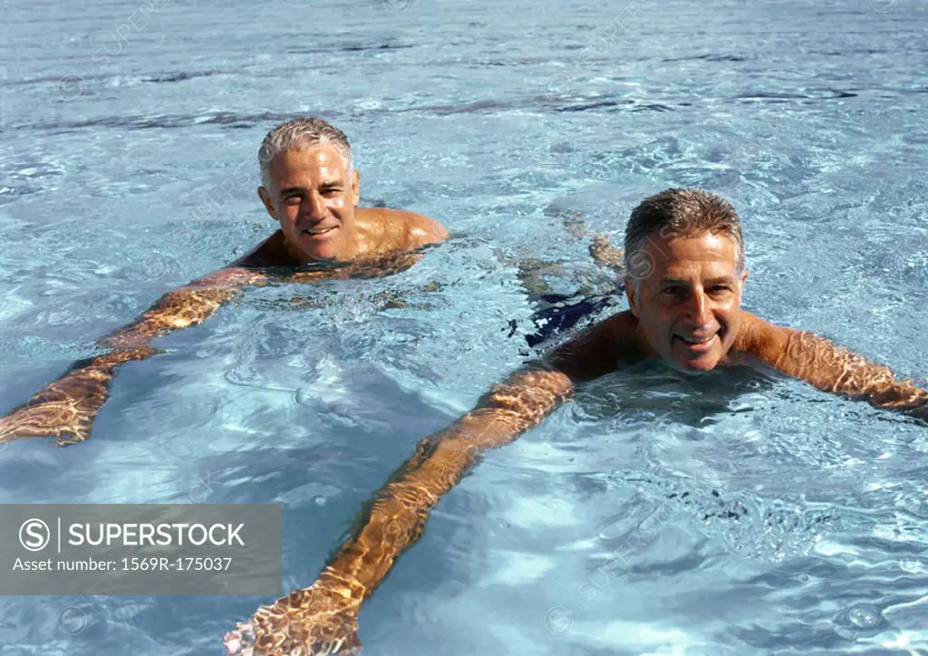 Two mature men in swimming pool, smiling