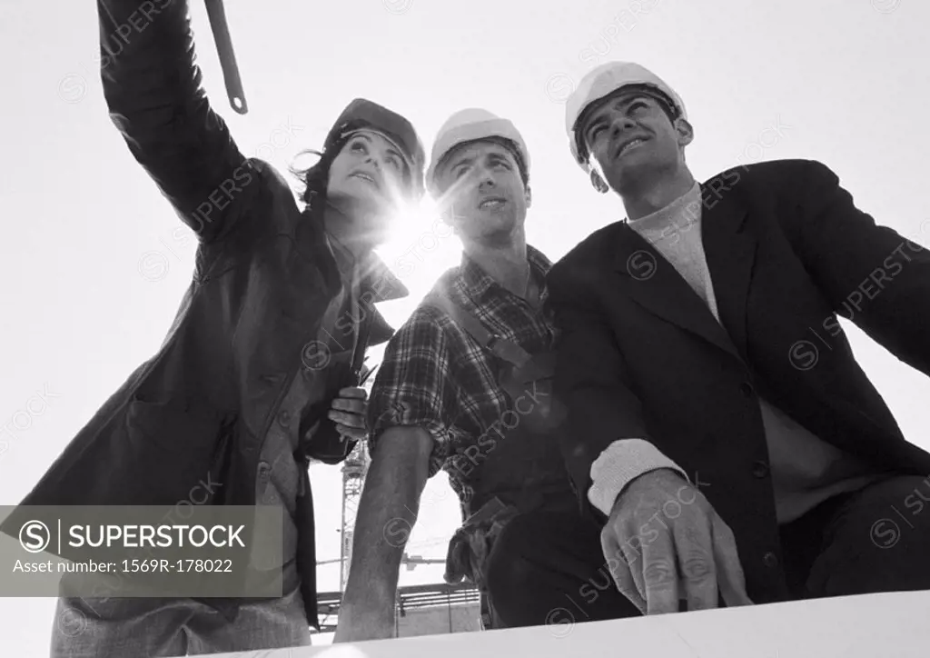 Two men and woman wearing hard hats, low angle view, b&w