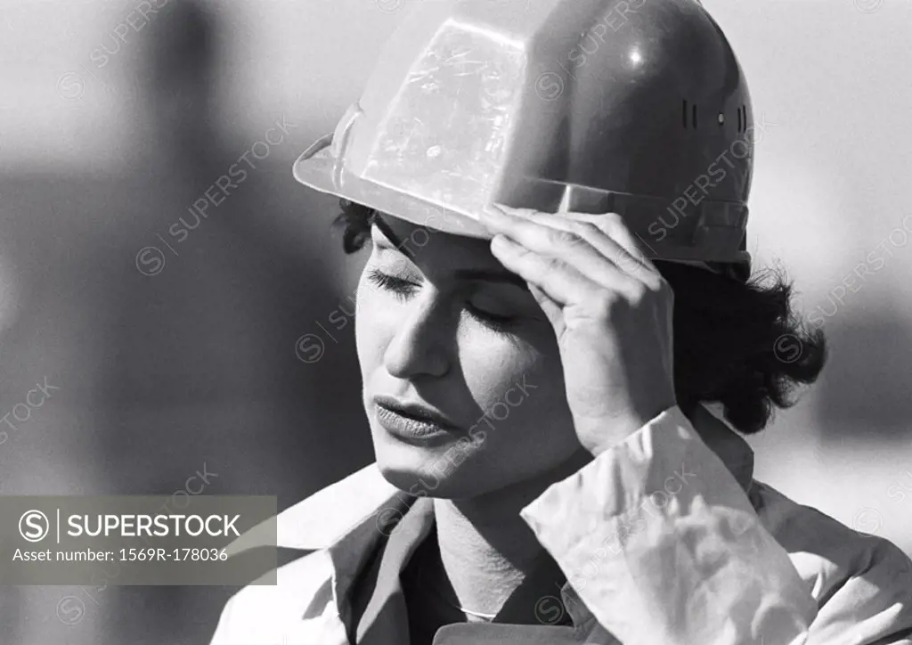 Woman holding hard hat, close-up, b&w