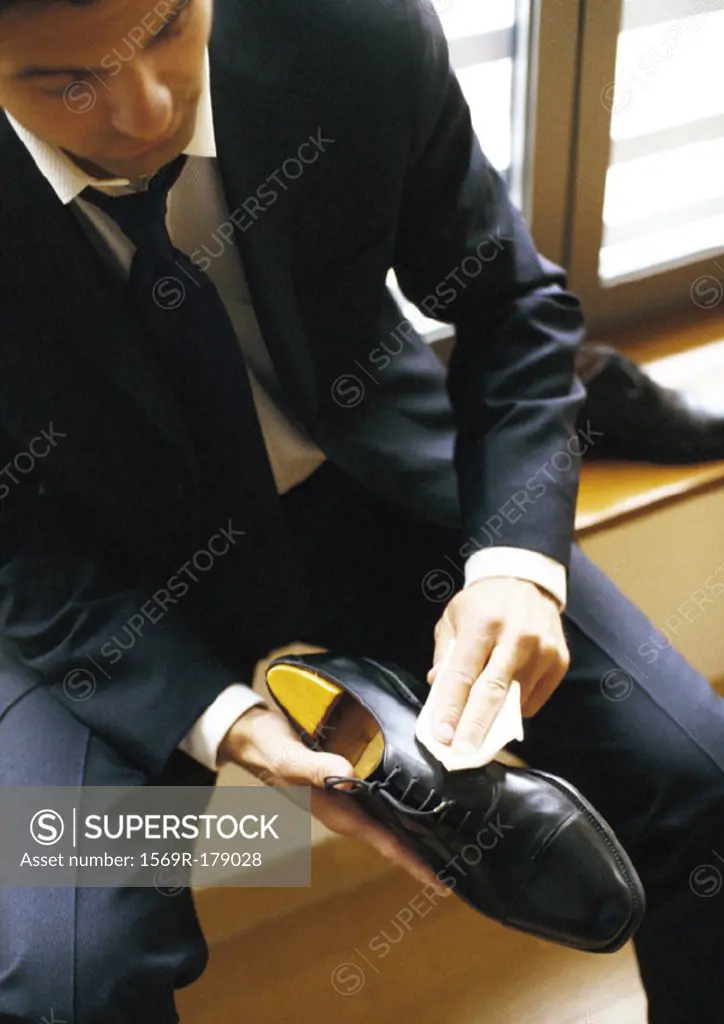 Man in suit polishing shoe, close-up