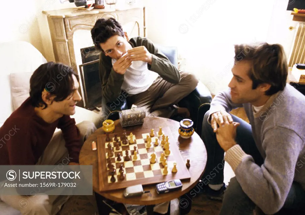 Three men in living room, two playing chess