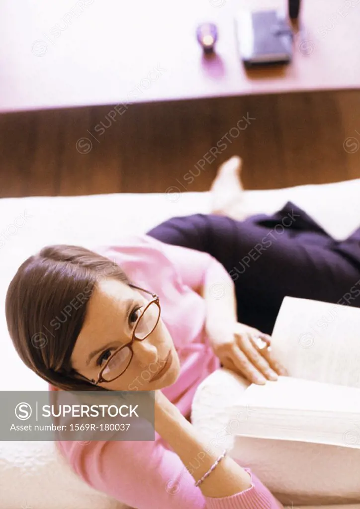 Woman with book, looking up at camera, portrait