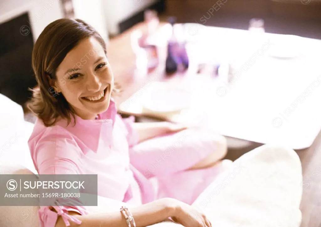 Woman sitting on sofa, smiling, portrait