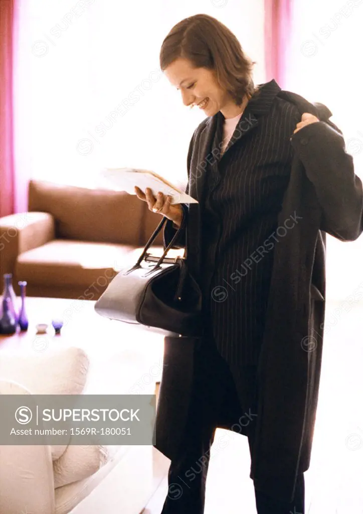 Woman putting coat on while reading