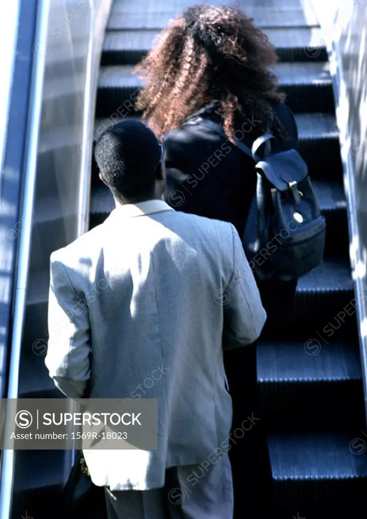 Couple riding escalator, rear view