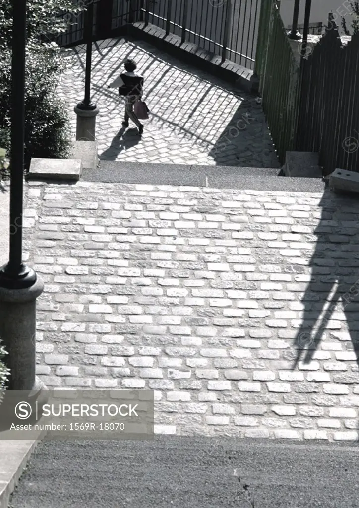 Person walking on cobblestone street, view from above