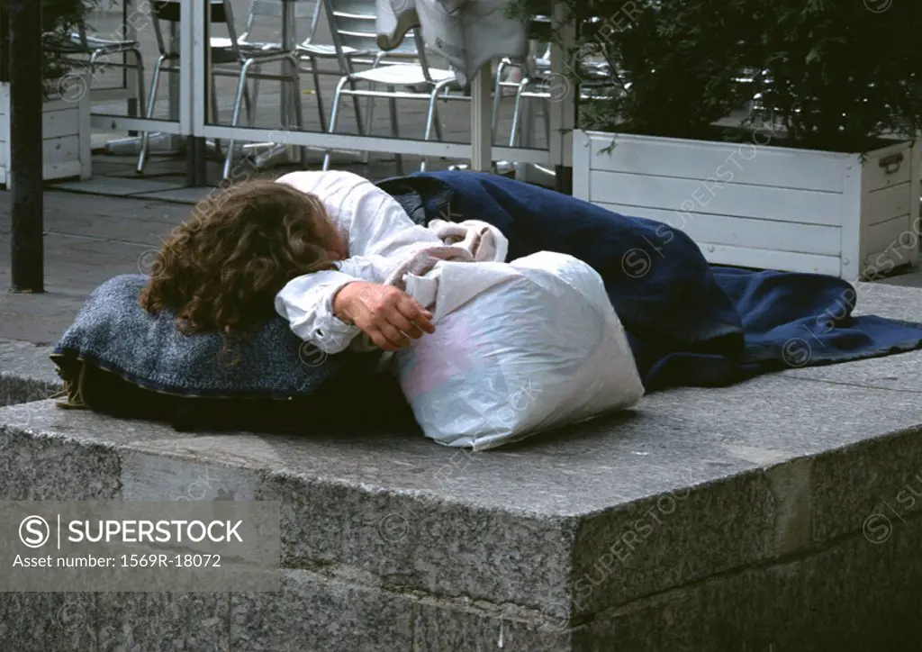 Person sleeping on sidewalk near café