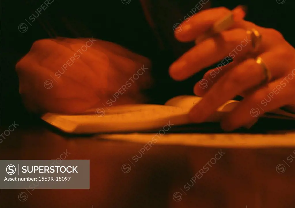 Woman holding cigarette in hand, blurred close up