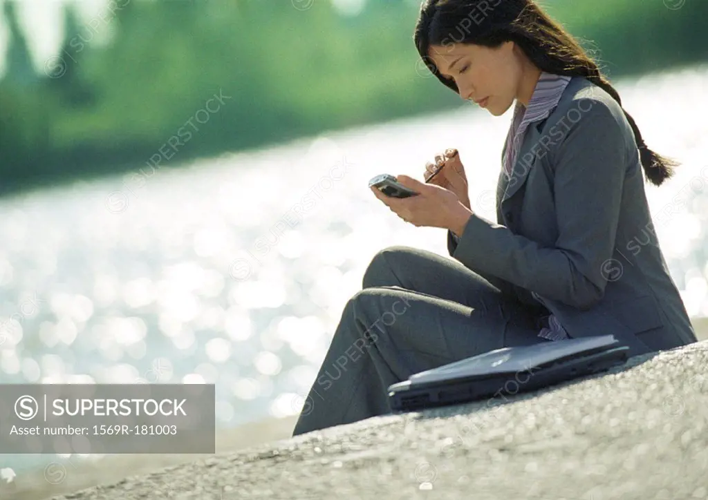 Businesswoman using hand held computer, outdoors