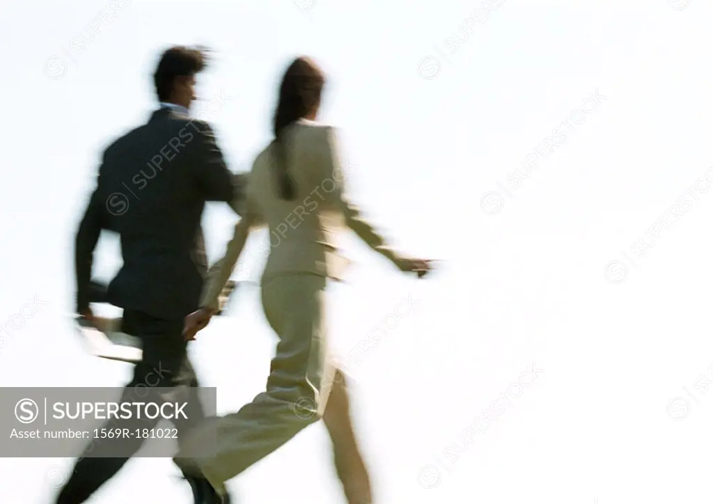 Businessman and woman walking, rear view, blurred