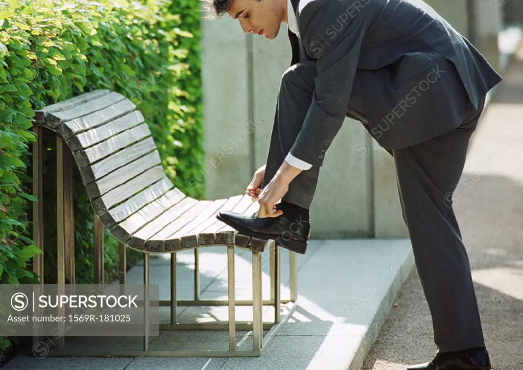 Businessman tying shoelaces on bench