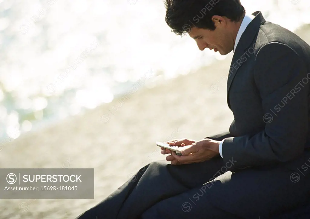 Businessman sitting with cell phone outdoors, close-up