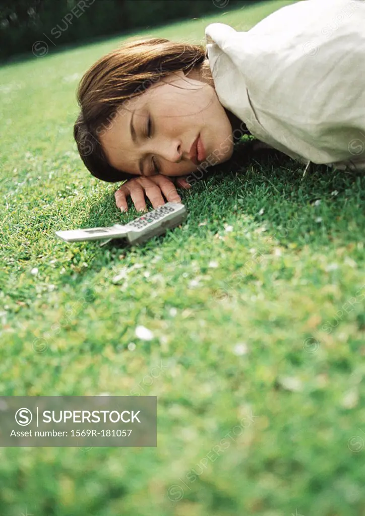 Woman lying on grass with cell phone near head, close-up