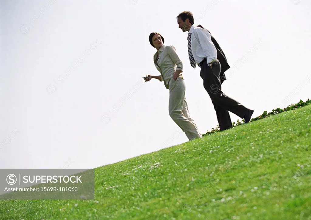 Businessman and woman walking on grass