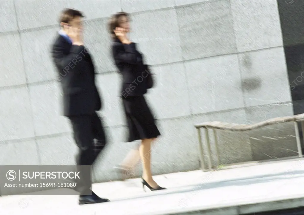 Businessman and woman using cell phones in street, full length, blurred motion