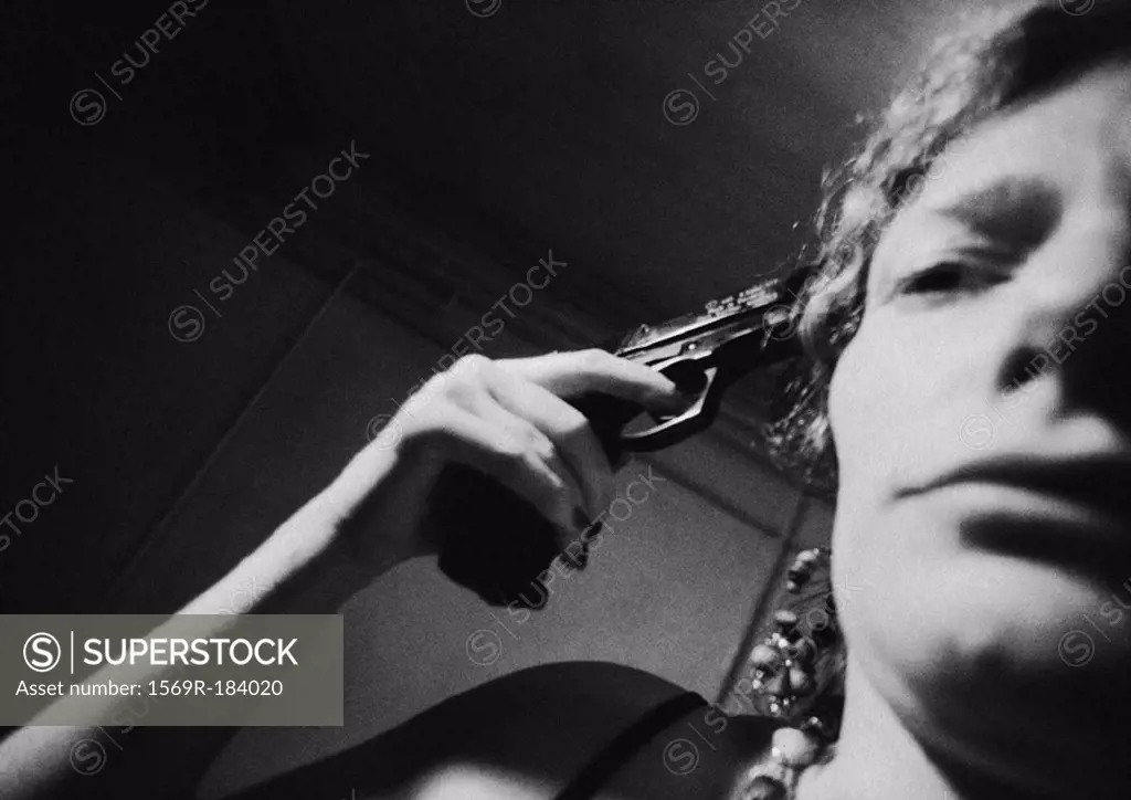 Woman with gun against temple, close-up, b&w