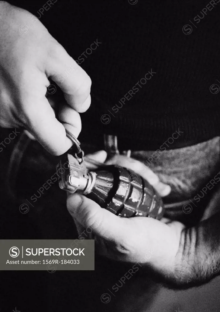 Man taking the pin out of grenade, close-up, b&w