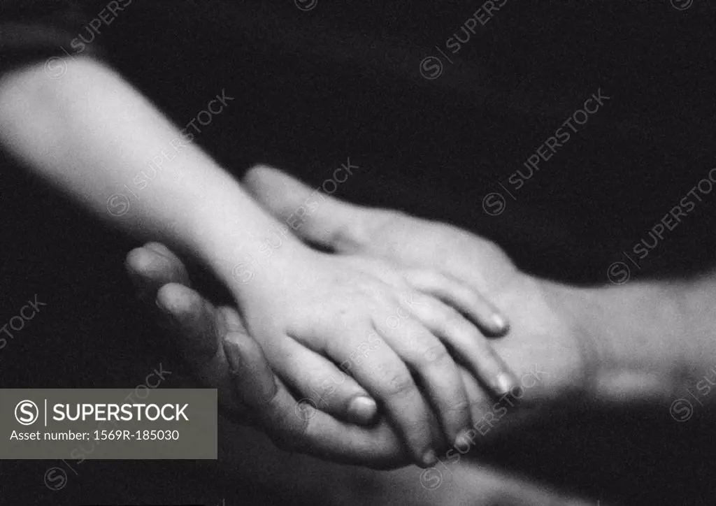 Adult´s hand holding child´s hand, close-up, b&w