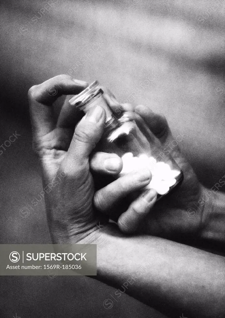 Hands holding bottle of pills, close-up, b&w